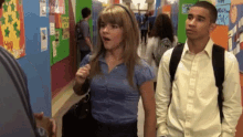 a boy and a girl are walking down a hallway in front of a sign that says " i love you "