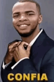 a man in a suit and tie is smiling while adjusting his tie .