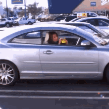 a silver car is parked in a parking lot in front of a store that has a sign that says ' walmart ' on it