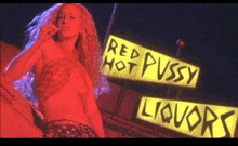 a woman smoking a cigarette in front of a red hot pussy liquor sign