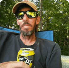 a man wearing sunglasses and a hat is holding a can of mikes lemonade