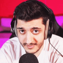 a man wearing headphones and a microphone is making a face .