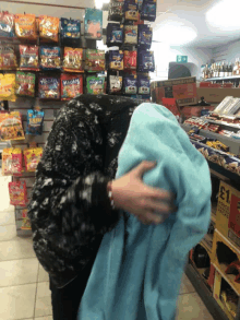 a person holding a blue blanket in front of a sign that says ' price packs ' on it