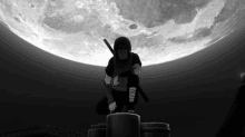 a black and white photo of a ninja with red eyes standing on top of a pillar in front of a full moon .