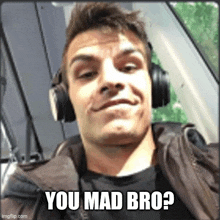 a man wearing headphones is making a funny face and says you mad bro ?