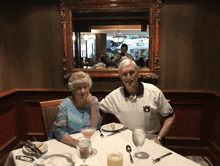 a man wearing an auburn shirt sits with his wife at a table