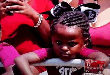 a little girl with a bow in her hair is watching a game between nc state and 12 florida state