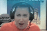 a woman wearing headphones and a red shirt is making a surprised face