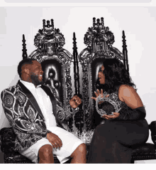 a man and a woman are sitting on thrones with crowns on their hands