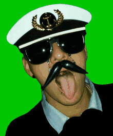 a man wearing a captain 's hat and sunglasses with an anchor on it sticks his tongue out