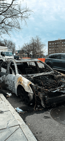 a burned out car is parked on the side of the road in front of a white truck that says oscar rabbit