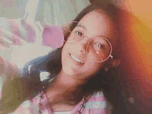 a girl wearing glasses and a plaid shirt smiles for the camera