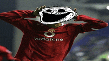 a man wearing a red vodafone shirt has a troll face on his face