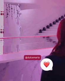 a woman with red hair is standing in front of a stage with a speech bubble that says @dulcemaria on it