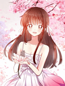 a girl in a white dress is holding a small bird in her hands