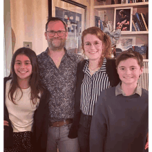 a family posing for a picture in front of a bookshelf with a picture of coles on it