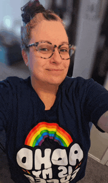 a woman wearing glasses and a ohaa t-shirt smiles for the camera