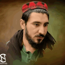 a man with a beard wearing a red and black hat and a green shirt has a logo for nangyal creations behind him