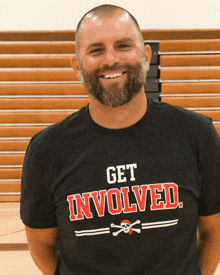 a man with a beard is wearing a black shirt that says get involved