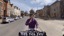 a man in a purple shirt is holding a microphone in front of a pioneer dj turntable that says " yes yes yes "