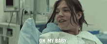 a woman in a hospital gown is holding a baby and saying oh my baby .