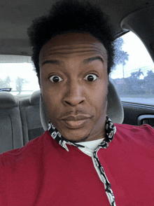 a man wearing a red shirt and a black and white scarf looks surprised