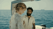 a man and a woman are standing on a boat with the word paused on the side