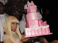 a woman is holding a pink cake with a barbie doll on top