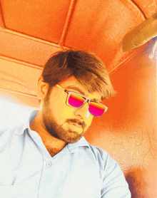 a man with a beard wearing sunglasses and a light blue shirt