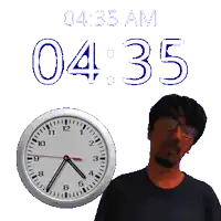 a man with glasses stands next to a clock that says 4:35 am