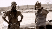 two men in military uniforms are standing next to each other on the beach .