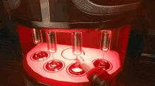 a person 's hand is reaching for a glass in a machine that has a red light on it