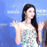a woman in a floral dress stands in front of a china mob sign