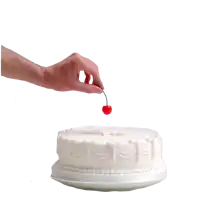 a hand is reaching for a cherry on a cake