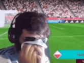 a man wearing headphones is crying while watching a soccer game