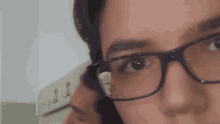 a close up of a person wearing glasses looking at a mirror