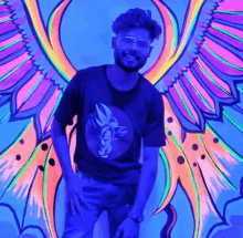 a man stands in front of a colorful painting with wings on it