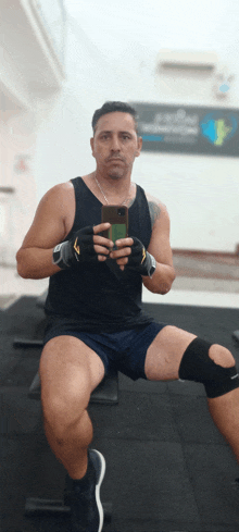 a man sitting on a bench taking a selfie with his cell phone