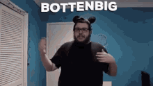 a man wearing mickey mouse ears and glasses is standing in front of a blue wall that says bottenbig