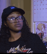 a woman wearing glasses and a hat with the letter t on it is standing in front of a calendar