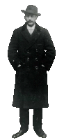 a black and white photo of a man wearing a hat and a long coat