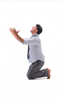 a man in a tie is kneeling down with his arms outstretched