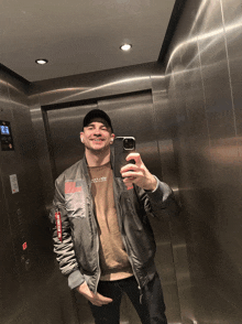 a man taking a picture of himself in an elevator with a phone case that says alpha industries