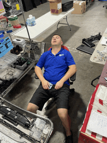 a man wearing a blue shirt that says ' electronics ' on it is sleeping in a chair