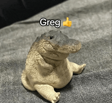 a statue of a crocodile with the name greg written above it