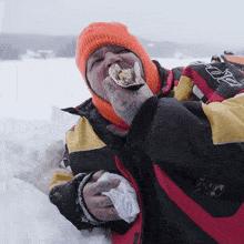 a man wearing an orange hat and a jacket that says ' ice ' on it is eating an oyster