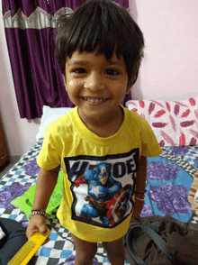 a young boy wearing a yellow shirt with a picture of captain america on it smiles