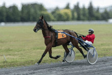 a man in a red jacket is riding a horse with the number 2 on the front