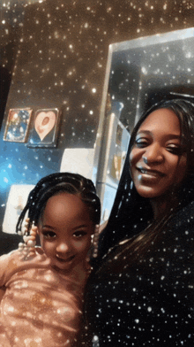 a woman and a little girl are posing for a picture in front of a refrigerator