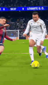 a soccer player wearing a white emirates jersey is kicking a yellow ball